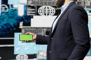 Businessman looks at green screen on phone for annual trends, planning a strategy for corporate success. Analyzing reports and infographics performance metrics to improve activity. photo