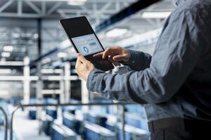 Close up of server room employee analyzing equipment metrics on device screen. Data center engineer looking at analysis charts on tablet from data gathered by infrastructure rigs photo