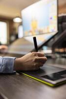 Closeup of designer using stylus on touchscreen device to refine and edit photographs. Selective focus on person adjusting color balance using graphic tablet, enhancing images for magazine publication photo