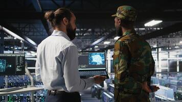 Military technicians in secure data center use laptop to monitor artificial intelligence systems. Army operators in server hub ensuring stable infrastructure for machine learning operations photo