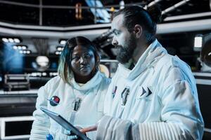 Team of cosmonauts operating spacecraft control interface, preparing for planetary mission outside. Orbital station colleagues monitoring system diagnostics, beginning landing procedures on planet photo