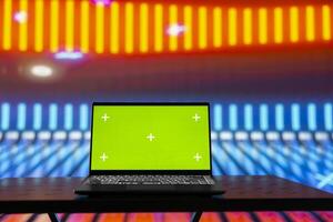 Empty glowing neon lit space with vivid colors and green screen display creates futuristic atmosphere for digital mockup, chroma key edits and artistic visual design in modern urban style. photo