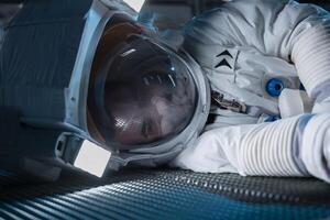 Astronaut losing life in accident onboard space station after sudden system failure during routine operations. Man lies motionless on spaceship floor, facing urgent medical emergency crisis photo