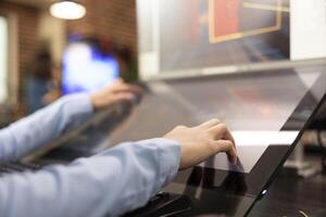Closeup of creative professional using touchscreen monitor on their office desk, developing 3d videogame scenes. Selective focus on hands of graphic expert utilizing digital screen for illustrations. photo