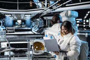 Female astronaut in spacecraft verifying navigation coordinates using laptop device. Woman in spaceship updating flight log on notebook during planetary exploration flight photo