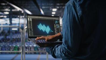 Close up of admin in data center using laptop to monitor neural network LLM visualization. Server hub IT expert overseeing rigs powering machine learning processes using notebook, photo