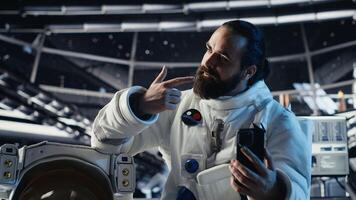 Astronaut records selfie with smartphone, making hand gestures, speaking to subscribers during Mars mission. Cosmonaut recording cosmic exploration content for followers photo