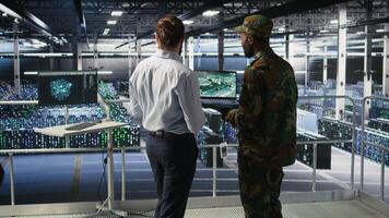Military IT specialists in server hub using laptop scanner tools to oversee battlefield during warfare. Army data center admins doing transmission analysis and live UAV system monitoring photo