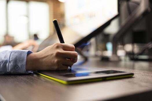 Selective focus of a designer holding a stylus pen drawing on a graphics tablet to edit images. Closeup of a creative individual sketching on digital device and modifying photographs. photo