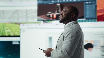 Smiling man using mobile phone surrounded by recommendations while browsing streaming services. Jolly african american man enjoys free time browsing favorite online clips on smartphone, camera A photo