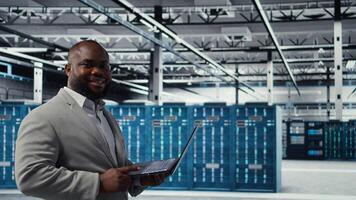 Data center software developer using tablet to do AI algorithms improvements. Programmer in server hub using laptop, maintaining databases supporting artificial intellgience applications, camera A photo