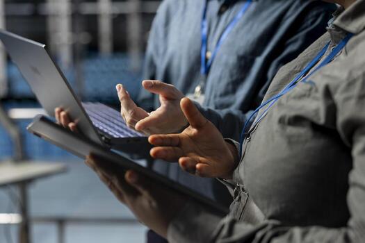 Server room coworkers doing brainstorming, backing up storage arrays using software on laptop. Team of data center engineers scanning hardware logs for faults to fix bugs using devices photo