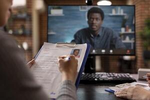 Selective focus of CV resume being analyzed by individual during call with african american businessman. Job application form of a black woman presented in virtual meeting with HR male manager. photo