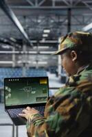 Close up of army expert in data center scanning terrain in real time using military satellite control. Military units wearing uniform in server farm managing orbital telemetry on laptop photo