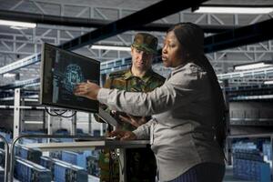 Server room army specialists reviewing insights to support operational strategies. Military server room colleagues checking mission critical systems using artificial intelligence photo