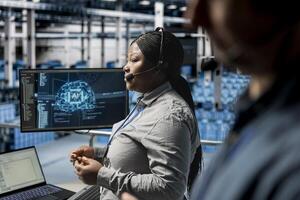 Server hub engineers diagnosing hardware failures using neural networks tech, guiding users. Teamworking employees using AI insights during voice calls in data center, resolving clients issues photo