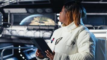 Female astronaut using tablet to check space station analytics after completing surface mission on unfamiliar planet. Woman inputting navigation coordinates, preparing for return to Earth photo