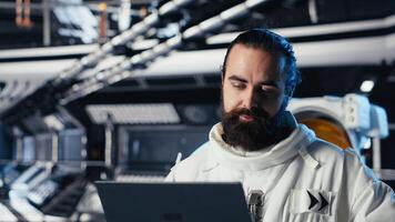 Astronaut checking human expansion in space mission data on laptop during cosmic journey. Orbit station crew managing systems using notebook during mankind survival expedition photo