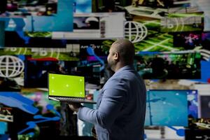 Professional content creator in a multitasking space holds green screen, leveraging social media, internet big data and cloud systems. Engaging followers to boost digital presence. photo