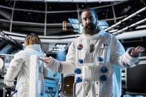Cheerful astronaut discusses with command center researchers on Earth during videocall from space station. Happy man in starship reports mission progress and confirms system status with ground control photo