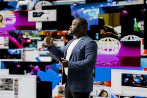 Black public speaker at a live convention engages the listeners with data on online trends, e commerce and communication using internet platforms. Real time social media visualization. photo