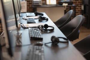 Empty office with sleek workstation, emphasizing a ready environment for company research and analysis. The vacant table is neatly arranged with headsets and clipboards for group of employees. photo