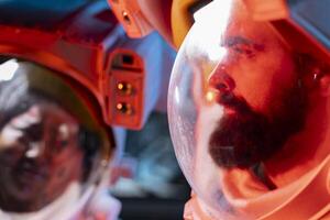 Close up of orbit station coworkers wearing helmet to protect against hazard, troubleshooting red light alert. Spaceship astronauts wearing protection gear against space radiation photo