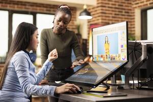 Multiethnic designers collaborate on photo retouching in studio, refining images for a project. In creative workspace, diverse women carefully select and color grade images for a commercial campaign.