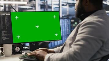 Data center system administrator inspecting gear using green screen PC, doing maintenance tasks. Server room worker using chroma key computer, conducting system checks, close up photo