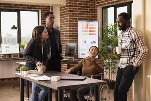 Business professionals engaging in a friendly discussion at office desk, fostering an inclusive and collaborative work environment. Multiethnic coworkers talking and having coffee. photo