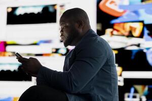 Black male user suffering from mental health issues due to toxic network, illustrating the overwhelming bad impact of internet trends, manipulation and the paranoia of comparison. photo