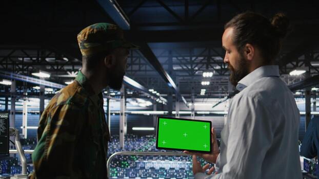 Military technicians in data center use green screen mockup tablet to monitor systems. Army operators in server room ensuring stable infrastructure using chroma key device, photo