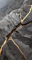Close-up of cracked dark stone with gold veins photo