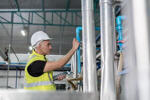 Engineers factory managers wearing safety helmet inspect the machines in the production line. Utility inspector check machine and test the system to meet the standard. machine, maintenance. photo