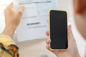 woman use phone scan barcode or QR codes to pay credit card bill after receiving document invoice. payment, receive, paying electricity. digital payments, technology, scanning, financial transactions photo