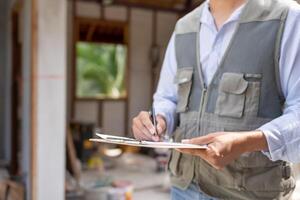 inspector engineer inspecting construction and quality assurance new house using a checklist. Engineers or architects or contactor work to build the house before handing it over to the homeowner photo