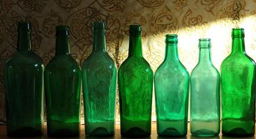Green Bottles in a Row a Display of Various Glassware on Wooden Surface photo
