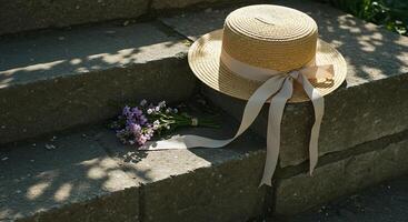 Straw Hat and Flower Bouquet Resting on Stone Steps in Sunlight photo