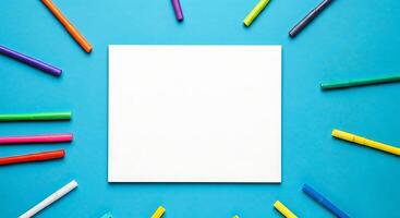 Blank paper with colorful markers on blue background photo
