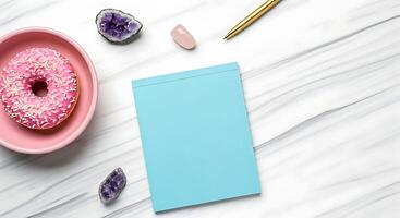 A pink plate with a donut, a notepad and a cup of coffee photo