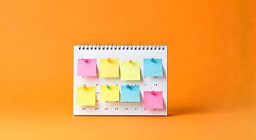 A calendar with sticky notes on it on an orange background photo