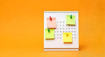 A calendar with sticky notes pinned to it on an orange background photo