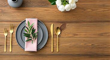 A table with a pink napkin, gold forks and silverware photo