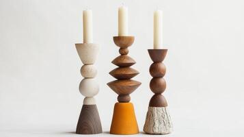Three distinct candlesticks in varied shapes and materials hold white candles, creating an elegant centerpiece for any setting photo