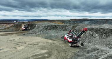 Excavator loading rocks in mining area under cloudy sky. Stock clip video