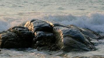Slow motion of wave crushing stone on a beach. video