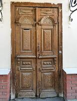 Ornate wooden double door with intricate carvings and weathered texture, architectural detail photo