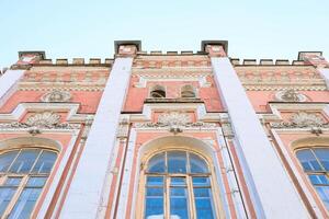 Architectural facade of historic building with ornate details and large windows against clear sky photo