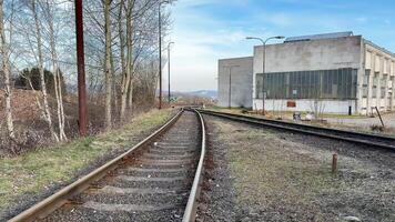 A serene and peaceful view of the winding railway tracks running beside a longabandoned industrial facility photo