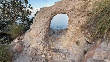 A serene rock arch framing stunning water views, perfect for nature lovers and adventurous travelers photo